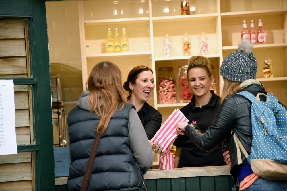 Two customers buying sweets from two National Trust members of staff